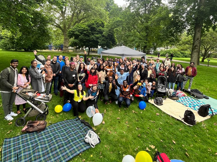 The IBC Essen church family gathered on the grass at the anniversary picnic, waving